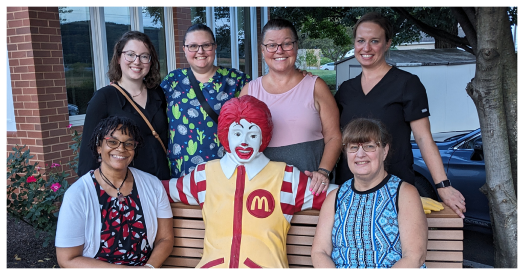A group of volunteers posing for a photo with a mcdonald's statue.